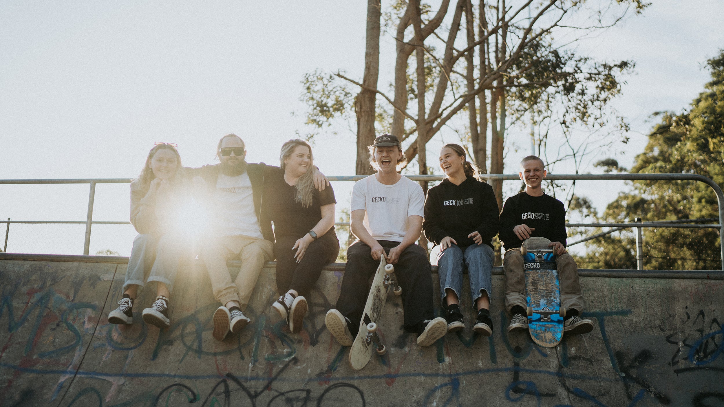 Gecko Skate team sits on the edge of the bowl.